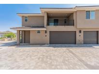 Modern two-story home featuring a balcony, gray garage doors, and a neutral color scheme against a clear blue sky at 2121 W Sonoran Desert Dr # 14, Phoenix, AZ 85085