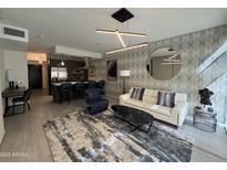 A modern living room with a view of a kitchen, designer lighting, modern furnishings, and accent wall at 7120 E Kierland Blvd # 404, Scottsdale, AZ 85254