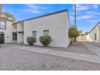 Charming stucco townhome with a well-maintained front yard, stone ground cover, and manicured landscaping at 1051 S Dobson Rd # 67, Mesa, AZ 85202