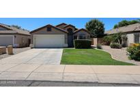 Charming single-story home featuring a well-maintained front yard with lush green grass and manicured landscaping at 15537 W Port Royale Ln, Surprise, AZ 85379