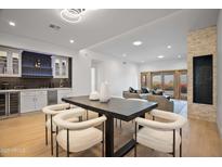 Spacious living area with a sleek dining table, modern lighting, and wet bar area, perfect for entertaining at 3800 E Lincoln Dr # 31, Phoenix, AZ 85018