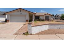 Traditional home featuring a two-car garage, neutral paint, and a low brick wall in the front yard at 136 E San Angelo Ave, Gilbert, AZ 85234