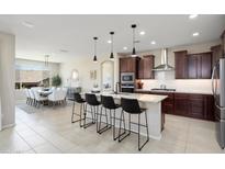 Open-concept kitchen flows to dining area, featuring granite countertops, dark cabinets, and stainless appliances at 26824 W Ponderosa Ln, Buckeye, AZ 85396