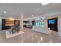 Open concept living room showcasing modern kitchen, dining area, fireplace and access to the backyard pool at 5324 E Hillery Dr, Scottsdale, AZ 85254