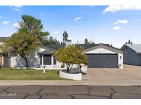 Charming single-story home with mature landscaping and a gray two-car garage door at 6550 W Wolf St, Phoenix, AZ 85033