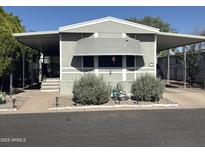 Charming mobile home featuring carport, awning, and well-maintained landscaping at 300 S Val Vista Dr # 54, Mesa, AZ 85204