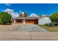 Charming brick home features a spacious driveway, mature trees, and lush landscaping at 3126 W Stella Ln, Phoenix, AZ 85017