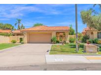 Inviting single-story home featuring a well-manicured lawn and a classic two-car garage, with a terra cotta colored roof at 9797 N 100Th Pl, Scottsdale, AZ 85258