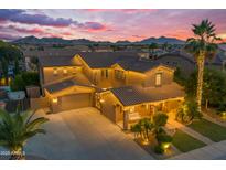 Stunning home exterior at dusk featuring a well-lit yard and a backdrop of majestic mountains at 21575 E Twin Acres Ct, Queen Creek, AZ 85142