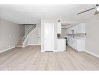 Open-concept living room features wood floors and seamlessly integrates the kitchen with white cabinets at 286 W Palomino Dr # 147, Chandler, AZ 85225