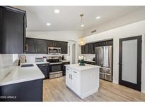 Well-lit kitchen featuring black cabinets, stainless steel appliances, an island, and light countertops at 4440 E Tether Trl, Phoenix, AZ 85050