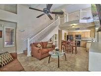 Spacious living room featuring a ceiling fan, staircase, and views into kitchen and upper level at 5640 E Bell Rd # 1034, Scottsdale, AZ 85254