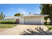 Home exterior featuring a two-car garage, a desert landscaped yard, and a decorative gate at 12826 W Maplewood Dr, Sun City West, AZ 85375