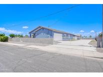 Charming single-story home featuring a blue stucco exterior and white gated entrance for added security at 12938 W Tara Ln, Surprise, AZ 85374