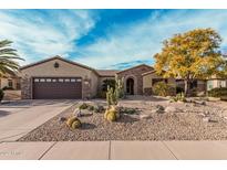 Charming home features a desert landscape, stone accents, and a brown two-car garage at 15452 W Skyview Way, Surprise, AZ 85374