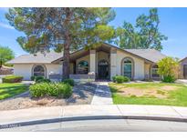 Charming single-story home featuring arched windows and a well-maintained lawn and lovely desert landscaping at 3611 E Dartmouth Cir, Mesa, AZ 85205