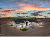 Stunning single-story home featuring a neutral palette, dark roof, and desert landscaping at twilight at 28848 W Grand Ave, Wittmann, AZ 85361
