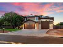 Stunning two-story home featuring a three-car garage and solar panels under a vibrant pink sunset at 3944 W Paradise Ln, Phoenix, AZ 85053