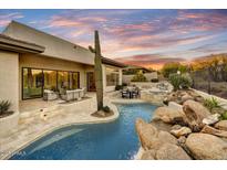 Inviting backyard with a sparkling pool, spa, water feature, and cozy seating under a colorful, picturesque sky at 7315 E Brisa Dr, Scottsdale, AZ 85266