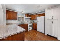 Charming kitchen featuring brown wooden cabinets, granite countertops, and essential modern white appliances at 9431 E Coralbell Ave # 192, Mesa, AZ 85208