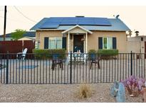 Charming bungalow-style home featuring solar panels, a cozy porch, and a wrought-iron fence at 2014 N 17Th Pl, Phoenix, AZ 85006