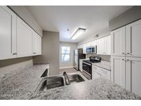 Modern kitchen with stainless steel appliances, white cabinets, and stylish granite countertops at 2025 E Campbell Ave # 137, Phoenix, AZ 85016