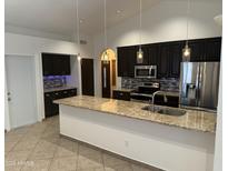 This open kitchen features modern appliances, granite countertops, and beautiful pendant lighting at 647 W Mission Dr, Chandler, AZ 85225