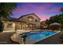 Inviting backyard pool and covered patio create an outdoor oasis for relaxation and entertaining under a colorful sky at 11866 N 143Rd Ave, Surprise, AZ 85379