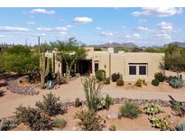 Beautiful tan home with mature landscaping, cactus, and mountain views in the background at 27203 N 64Th Way, Scottsdale, AZ 85266