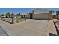 Charming single-level home featuring a well-manicured lawn and an expansive driveway at 5349 W Acapulco Ln, Glendale, AZ 85306