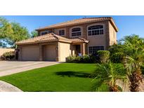 Two-story home with a tile roof, well-manicured lawn, and lush tropical landscaping at 9569 W Redbird Rd, Peoria, AZ 85383