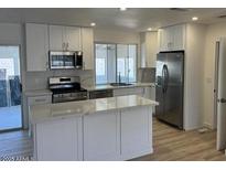 Bright kitchen features white cabinets, stainless appliances, and island with marble countertop at 18045 N 20Th N Ln, Phoenix, AZ 85023
