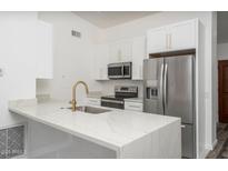 Bright kitchen features white cabinetry, stainless steel appliances, and a quartz countertop island with breakfast bar seating at 1351 N Pleasant Dr # 2011, Chandler, AZ 85225