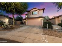 Charming two-story home featuring a neutral exterior, two-car garage, and mature desert landscaping at dusk at 21665 N 47Th Pl, Phoenix, AZ 85050