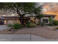 Charming single-story home with desert landscaping, mature trees, and a warm sunset backdrop at 9326 E Princess Dr, Mesa, AZ 85207