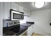 Well-lit kitchen with stainless steel microwave, oven and dark granite countertops at 3619 E Monterosa St # 202, Phoenix, AZ 85018