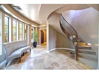 Bright foyer featuring travertine floors, a curved staircase with iron railing, and a comfortable sitting area at 3804 E Camelback Rd, Phoenix, AZ 85018
