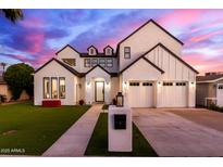 Stunning two-story home with a manicured lawn, modern black and white exterior paint, and spacious three car garage at 4131 E Roma Ave, Phoenix, AZ 85018