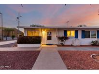 Charming single-story home with blue shutters, desert landscaping, and a welcoming entrance at dusk at 10516 W Peoria Ave, Sun City, AZ 85351
