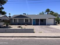 Charming single-story home featuring a well-manicured desert front yard, a bright blue front door, and a brick paved driveway at 3615 E Hearn Rd, Phoenix, AZ 85032