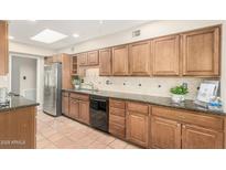 Charming kitchen with terracotta tile flooring, wooden cabinetry, and stainless steel appliances at 6025 N 10Th Pl, Phoenix, AZ 85014
