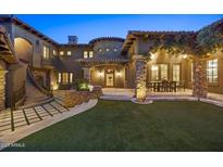 Beautiful home exterior featuring a stone facade, manicured lawn, outdoor dining, and elegant lighting at 9290 E Thompson Peak Pkwy # 470, Scottsdale, AZ 85255
