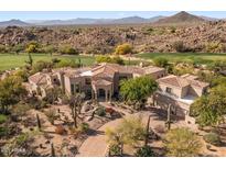 Expansive estate featuring stunning architecture, desert landscaping, and a tile roof, nestled within a lush golf course community at 10420 E Morning Vista Ln, Scottsdale, AZ 85262