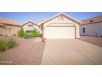 Inviting single-story home with a two-car garage, desert landscaping, and mature flowering bushes at 19961 N Coyote Lakes Pkwy, Surprise, AZ 85378