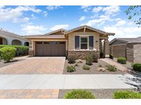 Charming single-story home with a two-car garage, brick driveway, and manicured landscaping at 20684 W Meadowbrook Ave, Buckeye, AZ 85396