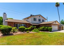 Charming two-story home featuring a well-maintained lawn, lush landscaping, and a brick facade with a two car garage at 2547 W Naranja Ave, Mesa, AZ 85202