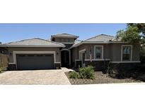 Charming single-story home with a paved driveway, gray garage door, stone accents, and well-maintained landscaping at 30287 N 115Th Dr, Peoria, AZ 85383