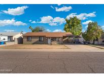 Charming single story home with covered parking and neutral tones against a vibrant blue sky and minimal landscaping at 3649 E Delcoa Dr, Phoenix, AZ 85032