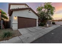 This is an exterior shot of the home with a two-car garage and desert landscaping at 10225 W Camelback Rd # 33, Phoenix, AZ 85037