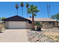 Charming single-story home featuring low-maintenance desert landscaping, palm trees, and a two-car garage at 15602 N 55Th Ave, Glendale, AZ 85306